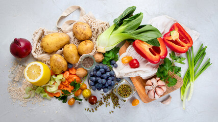 Selection of fresh raw vegetables, fruits and beans on light gray background.