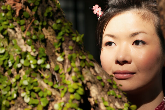 Close up portrait beautiful young woman looking away behind tree
