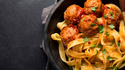 Tagliatelle with meatballs and tomato sauce on dark background. Italian food concept.