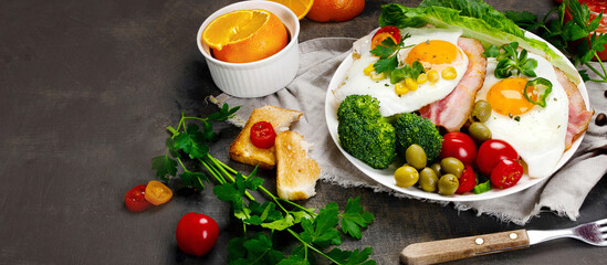 Fried eggs with vegetables on dark grey background