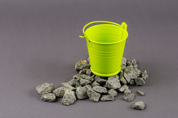 Gravel and a small green bucket on a gray background.