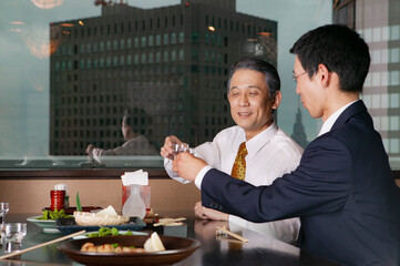 Japanese businessmen drinking with lunch in highrise restaurant
