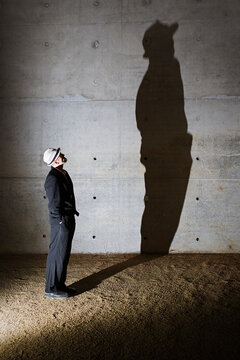 Man looking up at tall shadow on wall
