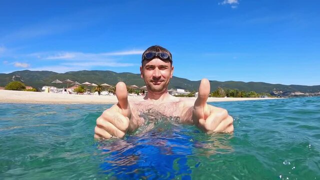 Man showing like in the water of the Aegean sea, nature on the background. Slow motion. Greece
