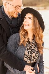 Beautiful young couple in boho style is standing by a lake. Lovers outside. Woman and man hug. Commitment. Couple outdoor spring