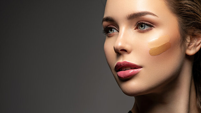 Face close-up with stripes of foundation on the face. The concept of makeup and cosmetics.