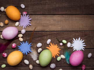 Obraz na płótnie Canvas bright Easter eggs on the background of a wooden table with feathers and ornaments with a copy of the space