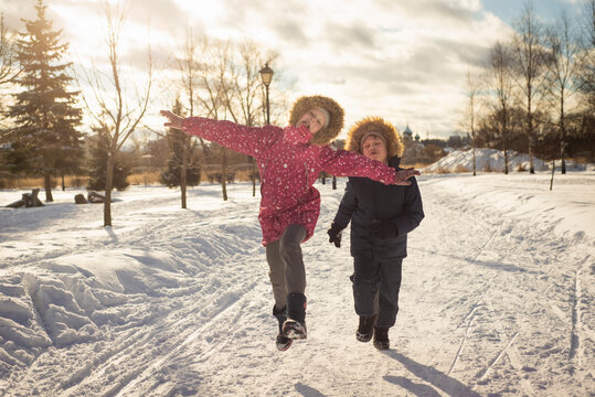 two children, a brother and a sister, run and play on a frosty sunny day, selective focus