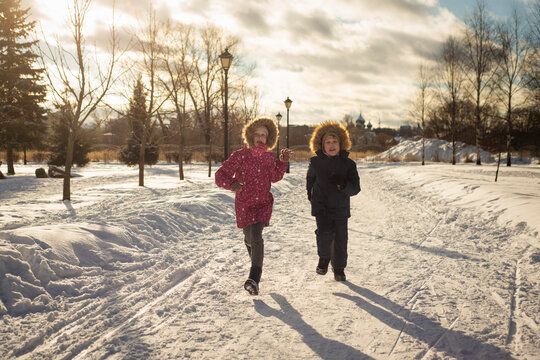 two children, a brother and a sister, run and play on a frosty sunny day, selective focus