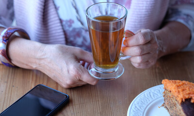 Close-up on woman's hand in coffee shop, enjoying a cup of tea and a carrot cake