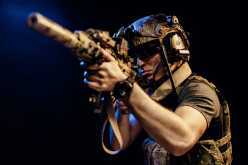 US special forces soldier looking at the aim ready to shoot against black dark background
