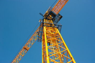 ron cabin of a yellow tower crane on a blue sky background close-up