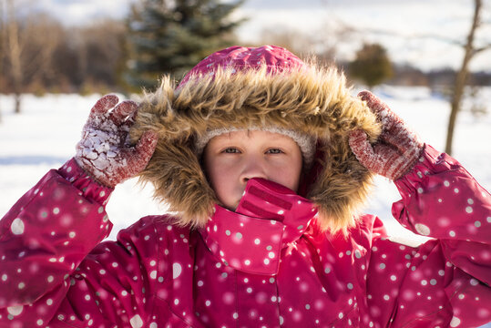 a girl in a pink jacket runs and plays on a frosty sunny day, selective focus