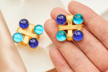 Hand hold Golden ear clip from 1980s, with blue glass jewelry inlaid on it.