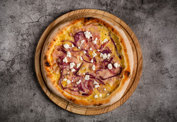 Pizza with ham, cheese and cottage cheese lies on a wooden board.