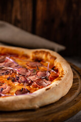 Italian pizza with meat, cheese and basil close up.