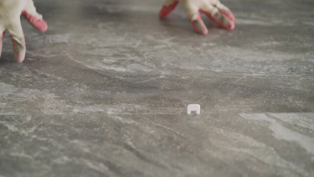 Laying floor ceramic tile. Renovating the floor. Construction workers laying tile over concrete floor using tile levelers, notched trowels and tile mortar.