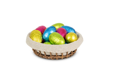 Colorful foil wrapped Easter eggs in basket isolated on white background.