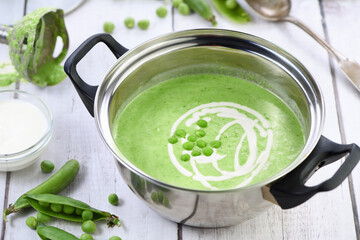 Saucepan of freshly cooked soup of mashed green peas and cream on the table.