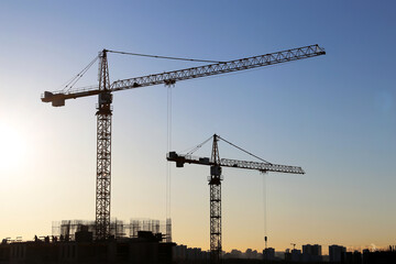 Tower cranes and construction site on sunrise background. Housing development, apartment block in...