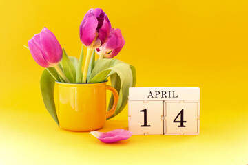 Calendar for April 14: cubes with the number 14 , the name of the month April in English, a bouquet...