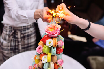 sparklers or burning candles on a birthday cake for the sixteenth birthday of macaroons and flowers...