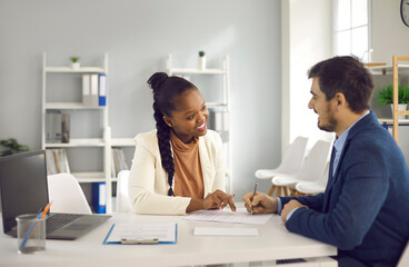 American african female lawyer insurance broker explaining contract details to cuacasian male...
