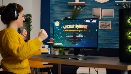 Exciting professional esport gamer celebrates championship victory. Woman winning space shooter video game. Online cyber gaming tournament live streaming event using technology network wireless © DC Studio