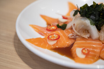 Spicy salmon salad. The plate of thin-sliced salmon with spicy dipping sauce.