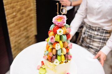 sparklers or burning candles on a birthday cake for the sixteenth birthday of macaroons and flowers close-up.