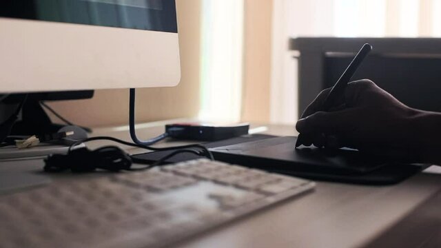 Man hand drawing in pen tablet in front of computer close up footage