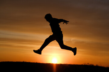 Fototapeta na wymiar Man silhouette jump at sunset background at summer.