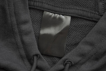Blank black laundry care clothes label on black fabric texture background