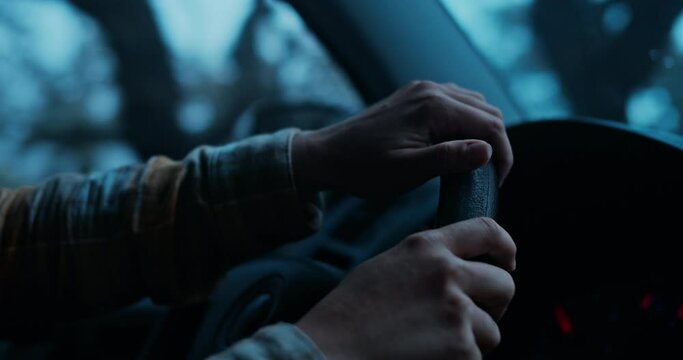 Cinematic and moody atmosphere shot of woman drive through dark foggy forest. Female hands hold steering wheel of car. Wanderlust road trip lifestyle concept. Vanlife adventure in cold winter mood