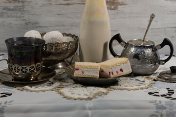 A cup of tea, a sugar bowl and cakes in a candy bowl. 