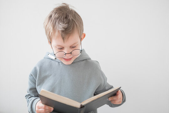 Cute Cheerful Little boy reading a book in glasses. Smart preschooler. Back to school concept	