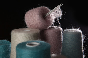 Multicolored natural wool yarn on a black background. Skeins with fluffy mohair. Concept of a...