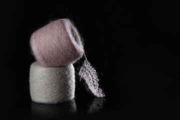 Pink and beige mohair in tangles. Skeins of yarn with fluffy mohair on a black background. Natural wool yarn. The concept of a hobby. Handmade work. Free space. Black background.