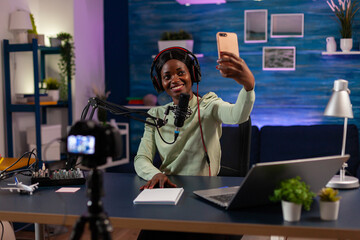 African woman using smartphone to take photo in entertainment business recording episode. On-air...
