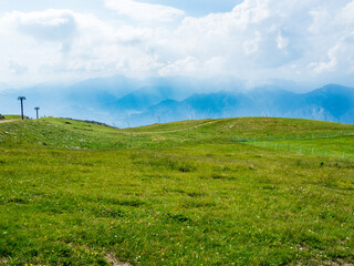 The view is over the mountains of Monte Baldo in Malcesine in Italy in a green meadow.