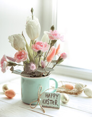 Easter floral arrangement with natural flowers and the inscription Happy Easter on the card.
