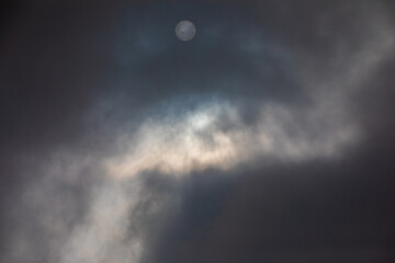 A pale sun shines from the dark clouds