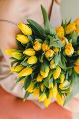 A large bouquet of yellow tulips in the hands of the girl. Spring mood.