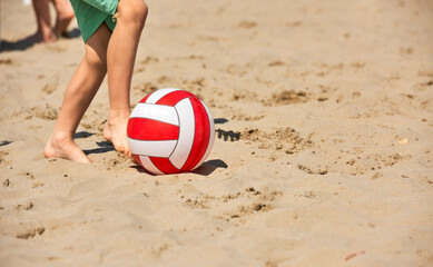 Child plays with a soccer ball at the beach, summer on a sunny day.