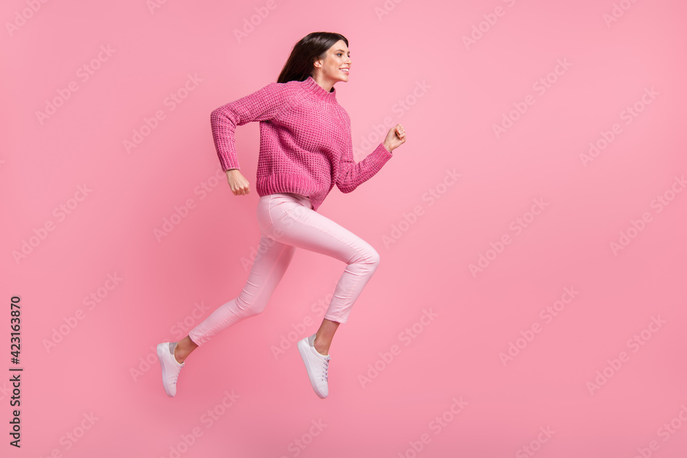 Poster Full size profile photo of brunette nice girl jump run wear pink sweater pants sneakers isolated on crimson background