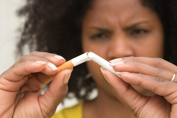 African american woman with afro hair and yellow t-shirt breaking a cigarette with her hands.