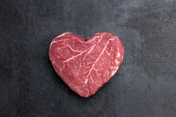 Obraz na płótnie Canvas Heart shape raw fresh beef steak on metal background