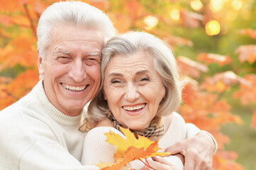 portrait of beautiful happy senior couple with autumn leaves