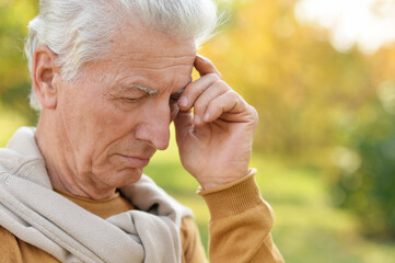 portrait of  senior man  in  park with headache