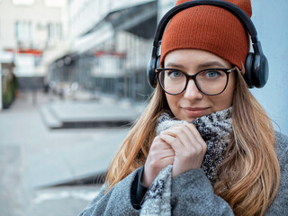 portrait of a beautiful girl with poor eyesight in headphones on a gray background